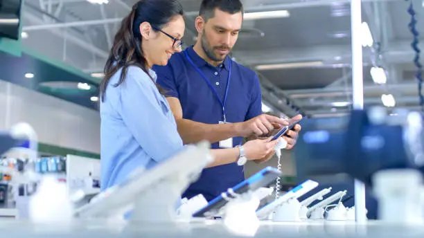 Professional demonstrating electronics to a customer at an electronics outlet in Fresno